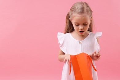 Photo of Little girl with shopping bag on pink background, space for text