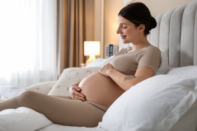 Photo of Beautiful pregnant woman on bed at home. Space for text