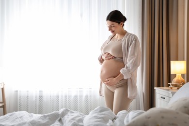 Photo of Beautiful pregnant woman near window at home. Space for text