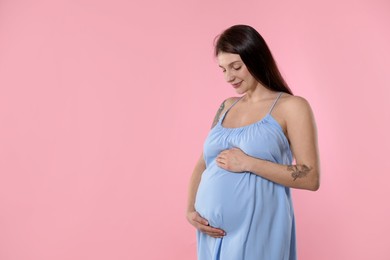 Photo of Beautiful pregnant woman with cute belly on pink background. Space for text