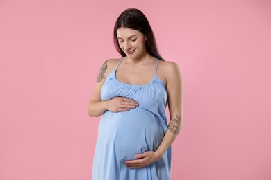 Photo of Beautiful pregnant woman with cute belly on pink background