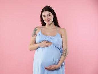 Photo of Beautiful pregnant woman with cute belly on pink background