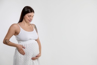 Photo of Beautiful pregnant woman with cute belly on white background. Space for text