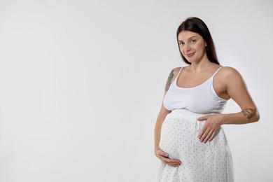 Photo of Beautiful pregnant woman with cute belly on white background. Space for text