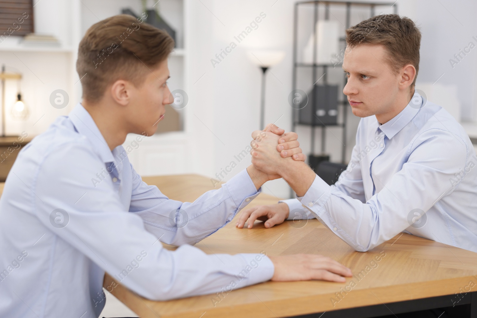 Photo of Competition concept. Businessmen arm wrestling at table in office