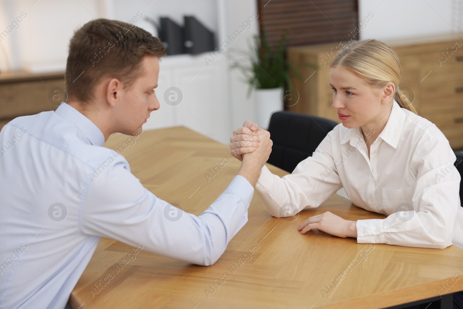 Photo of Competition concept. Businesspeople arm wrestling at table in office