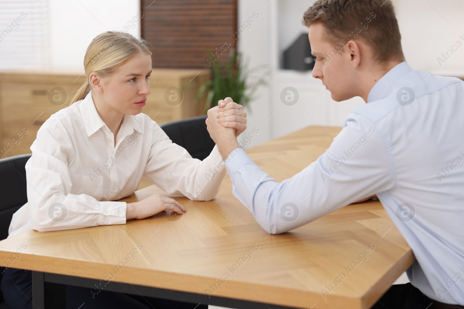 Photo of Competition concept. Businesspeople arm wrestling at table in office