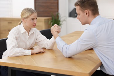 Competition concept. Businesspeople arm wrestling at table in office