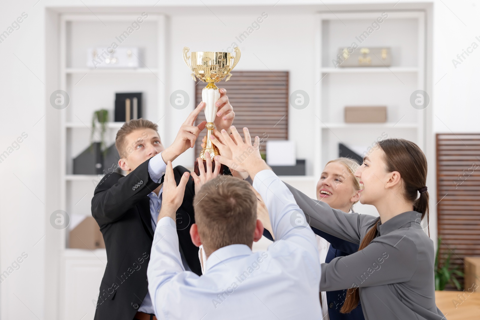 Photo of Competition concept. Group of businesspeople with golden trophy in office