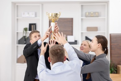 Competition concept. Group of businesspeople with golden trophy in office