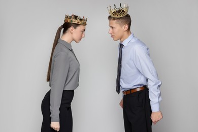 Photo of Business competition. Colleagues in golden crowns looking at each other on grey background