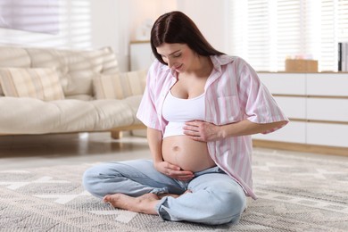 Photo of Beautiful pregnant woman with cute belly on floor at home