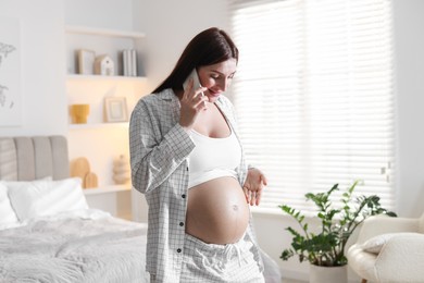 Beautiful pregnant woman talking on phone at home