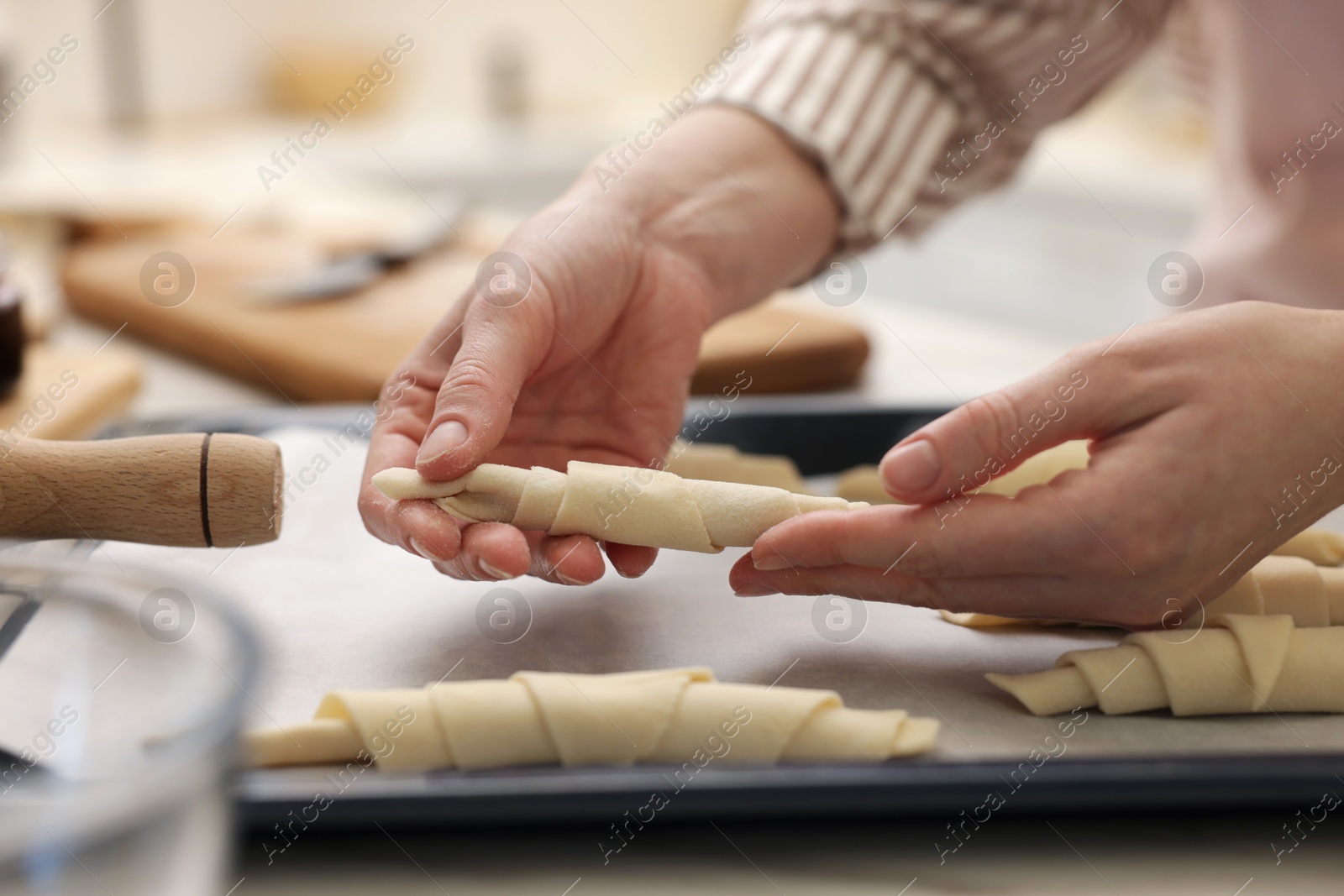 Woman putting raw croissants onto baking sheet at table, closeup Photo of Woman putting raw croissants onto baking sheet at table, closeup