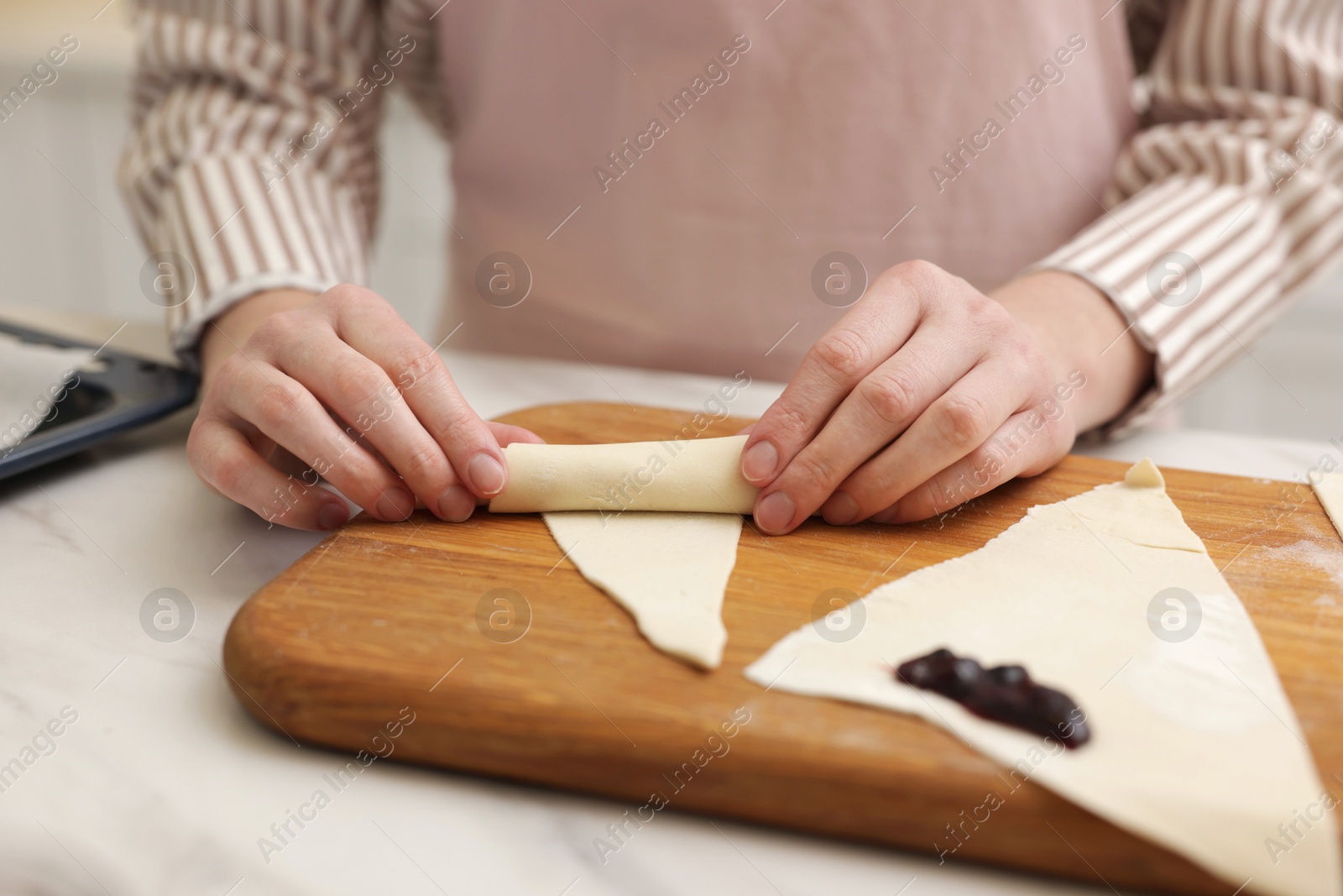 Woman rolling croissant with jam from fresh dough at table, closeup Photo of Woman rolling croissant with jam from fresh dough at table, closeup