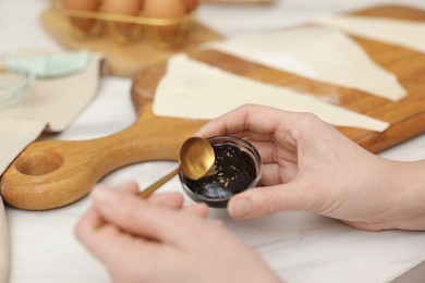 Photo of Woman with jam and fresh dough at white marble table, closeup. Making croissants