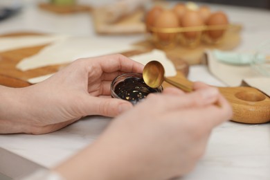 Photo of Woman with jam at white table, closeup. Making croissants