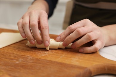 Photo of Woman making croissant at table indoors, closeup