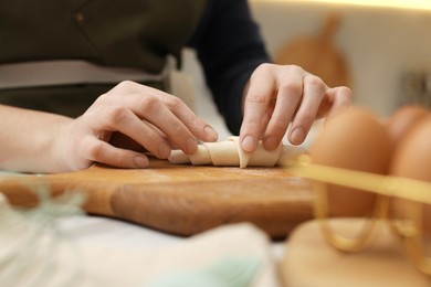 Photo of Woman making croissant at table indoors, closeup