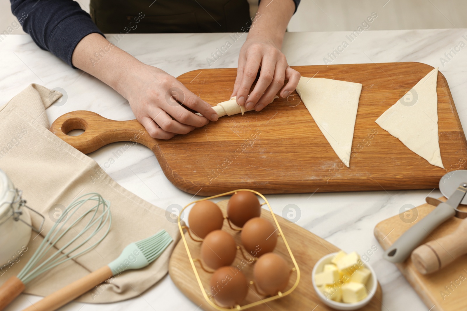 Woman rolling croissant from fresh dough at white marble table, closeup Photo of Woman rolling croissant from fresh dough at white marble table, closeup