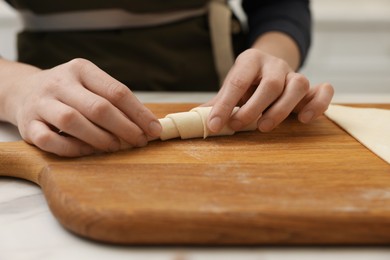 Photo of Woman making croissant at light table indoors, closeup