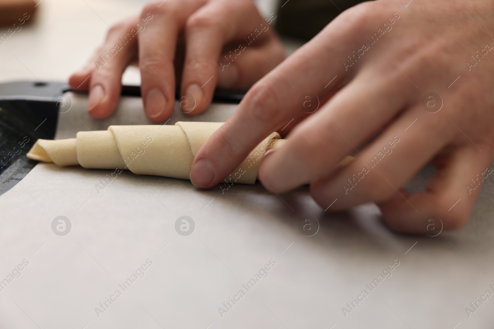 Woman putting raw croissant onto baking sheet, closeup Photo of Woman putting raw croissant onto baking sheet, closeup