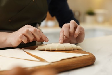 Woman making croissant at light table indoors, closeup