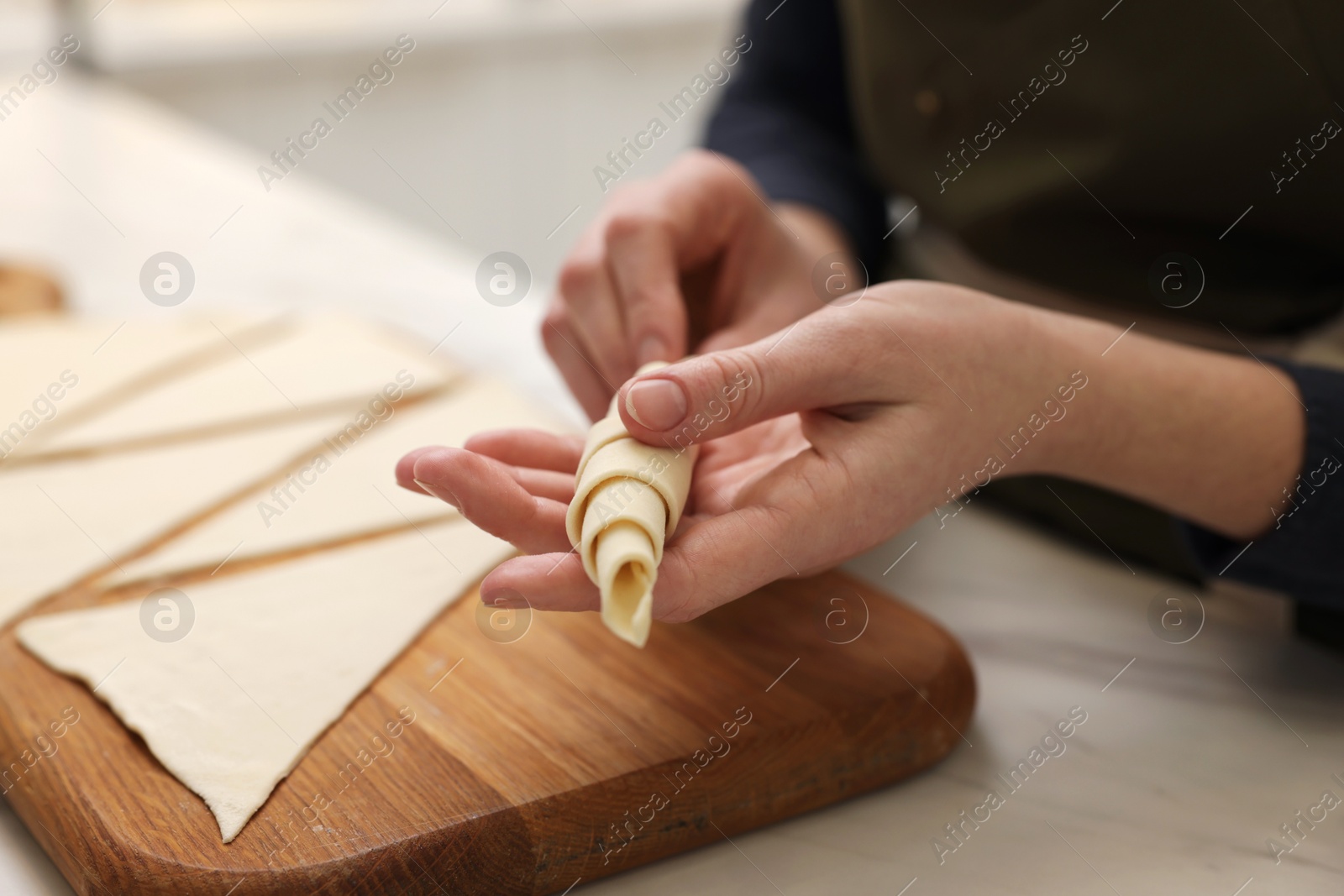 Woman making croissant at light marble table indoors, closeup Photo of Woman making croissant at light marble table indoors, closeup