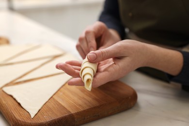 Photo of Woman making croissant at light marble table indoors, closeup