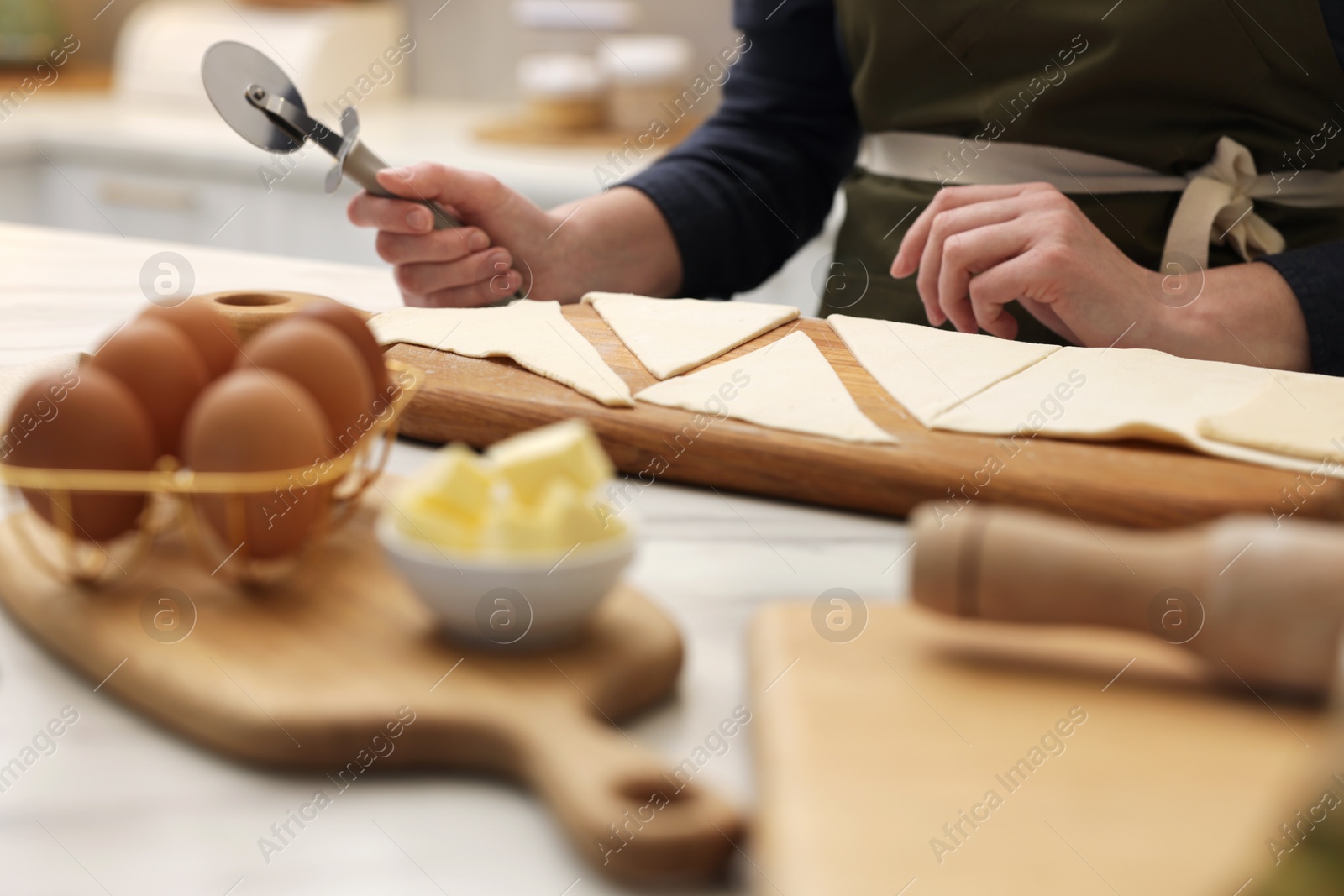 Woman with dough cutter and ingredients at light table indoors, selective focus. Making croissants Photo of Woman with dough cutter and ingredients at light table indoors, selective focus. Making croissants
