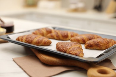 Photo of Freshly baked croissants on light table indoors, closeup