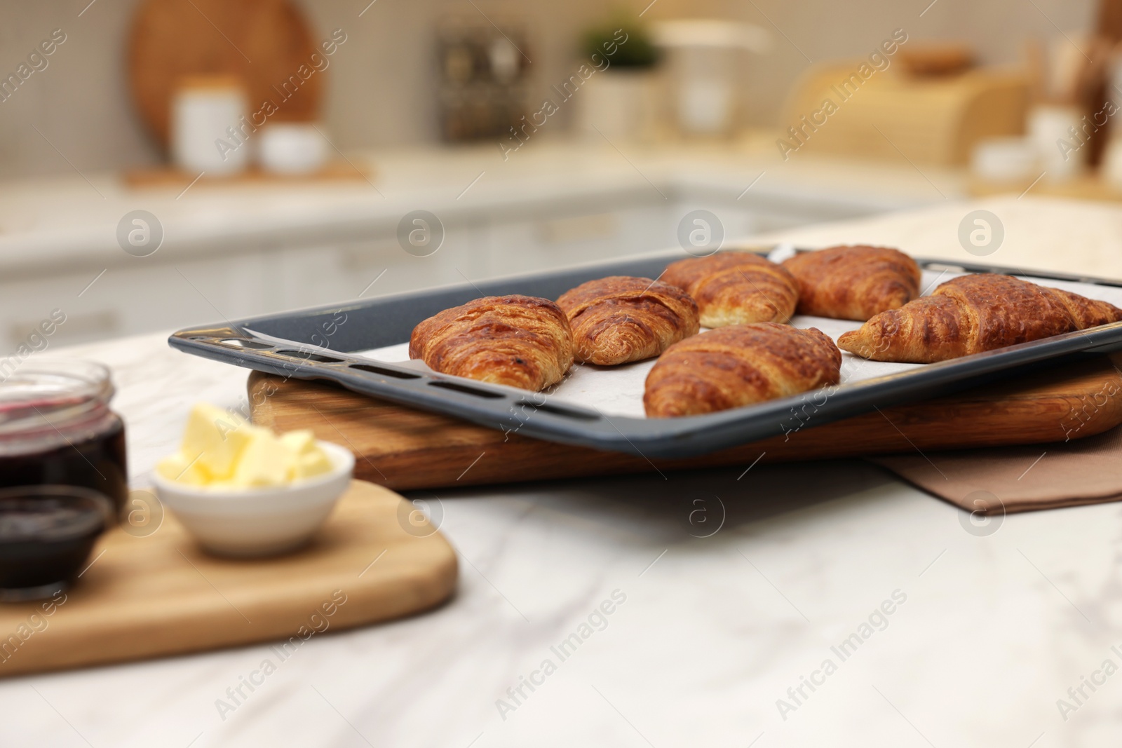 Freshly baked croissants, butter and jam on white marble table indoors, selective focus Photo of Freshly baked croissants, butter and jam on white marble table indoors, selective focus