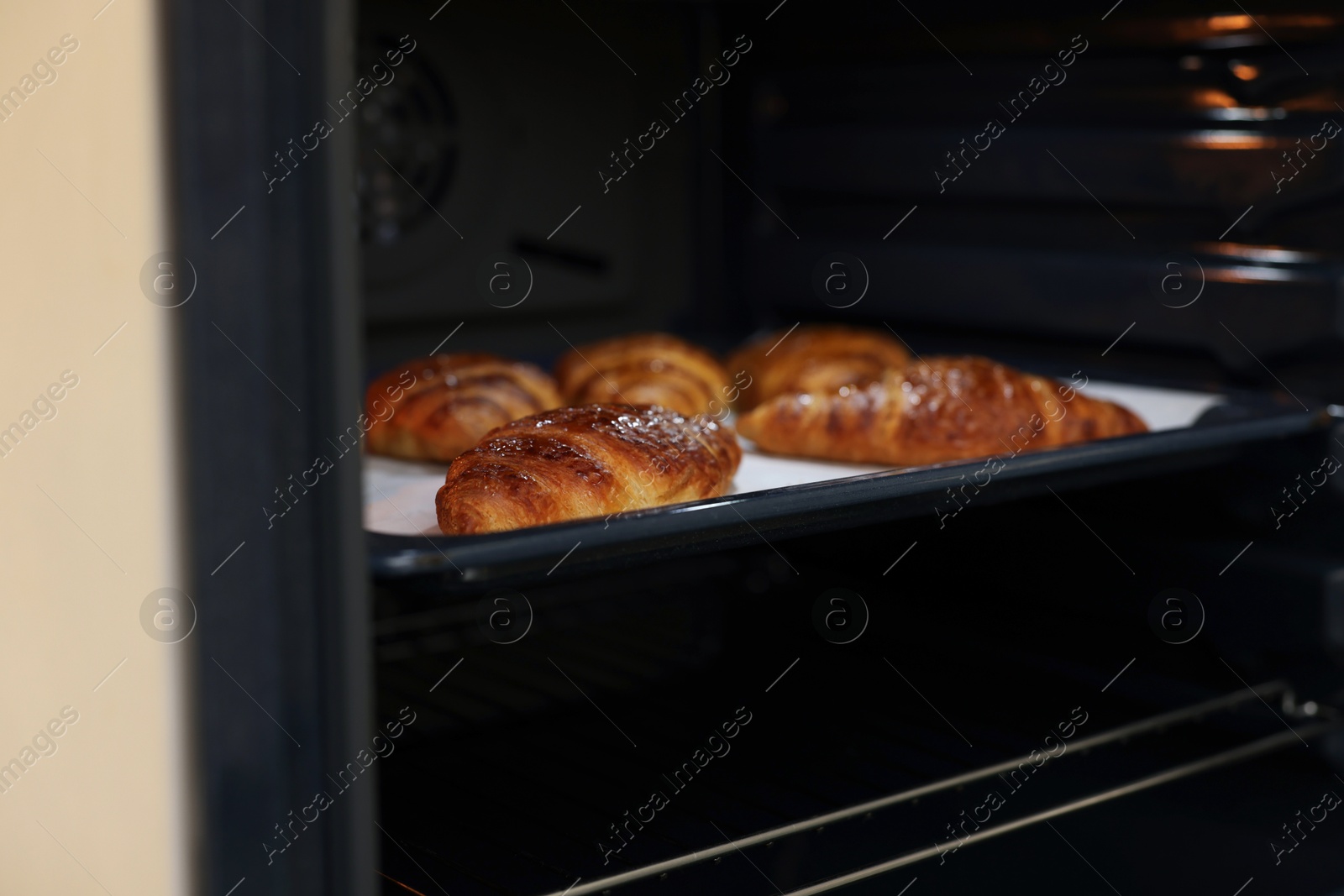 Freshly baked croissants on baking sheet in oven Photo of Freshly baked croissants on baking sheet in oven