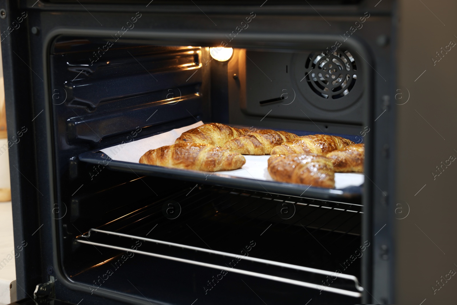Freshly baked croissants on baking sheet in oven Photo of Freshly baked croissants on baking sheet in oven