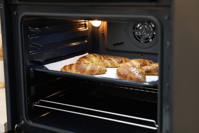 Photo of Freshly baked croissants on baking sheet in oven