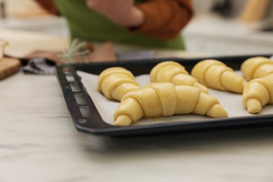 Photo of Raw croissants on white marble table and woman, selective focus