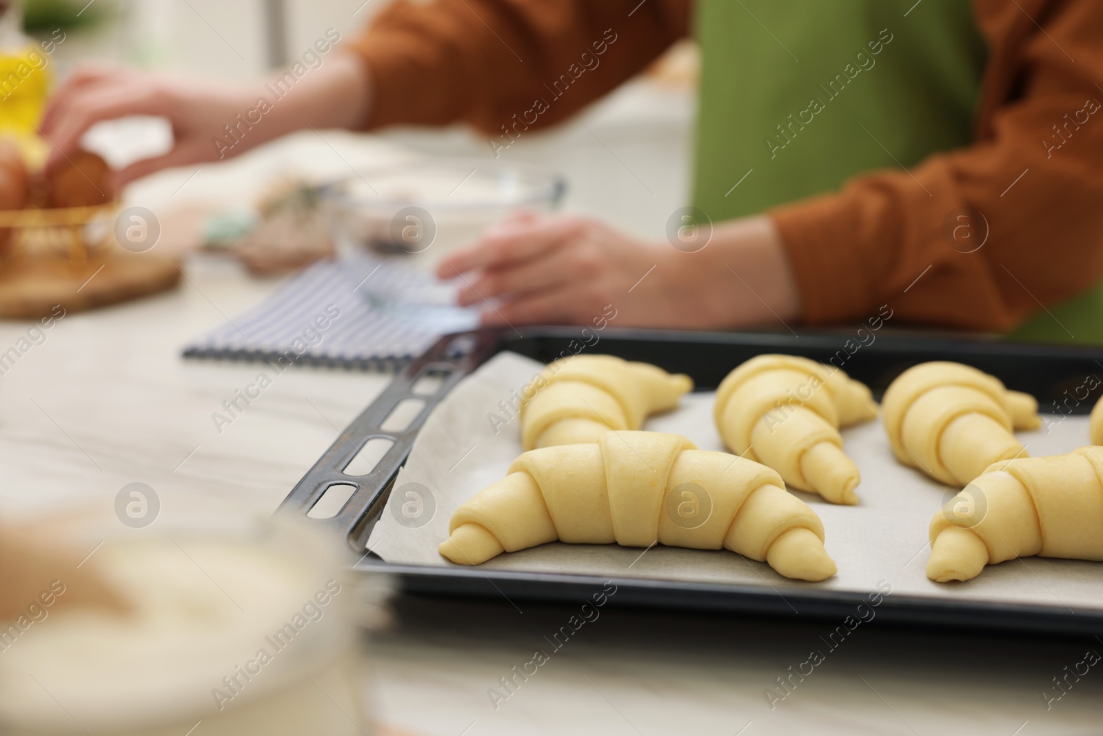 Photo of Woman making croissants at white marble table, selective focus