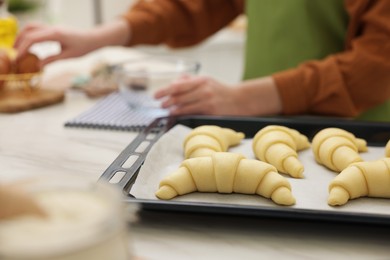 Woman making croissants at white marble table, selective focus