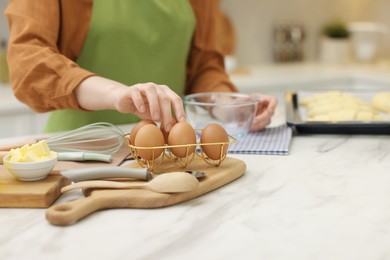 Photo of Woman taking egg at white marble table in kitchen, closeup