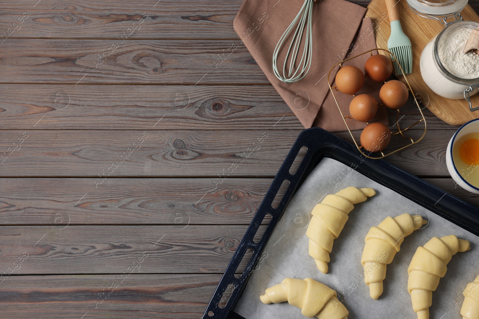 Raw croissants, ingredients and kitchenware on wooden table, flat lay. Space for text Photo of Raw croissants, ingredients and kitchenware on wooden table, flat lay. Space for text