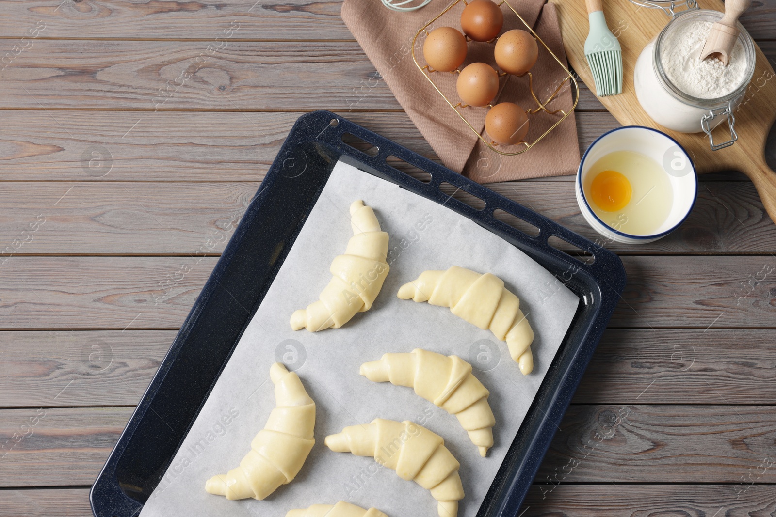 Raw croissants, ingredients and kitchenware on wooden table, flat lay Photo of Raw croissants, ingredients and kitchenware on wooden table, flat lay