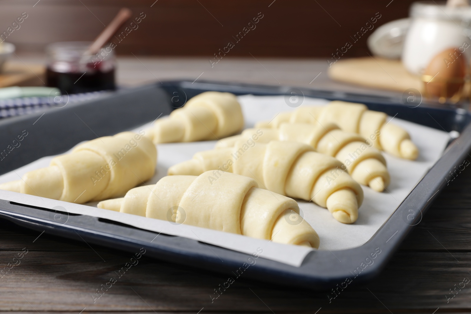 Photo of Fresh raw croissants on wooden table, closeup