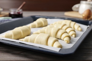 Fresh raw croissants on wooden table, closeup