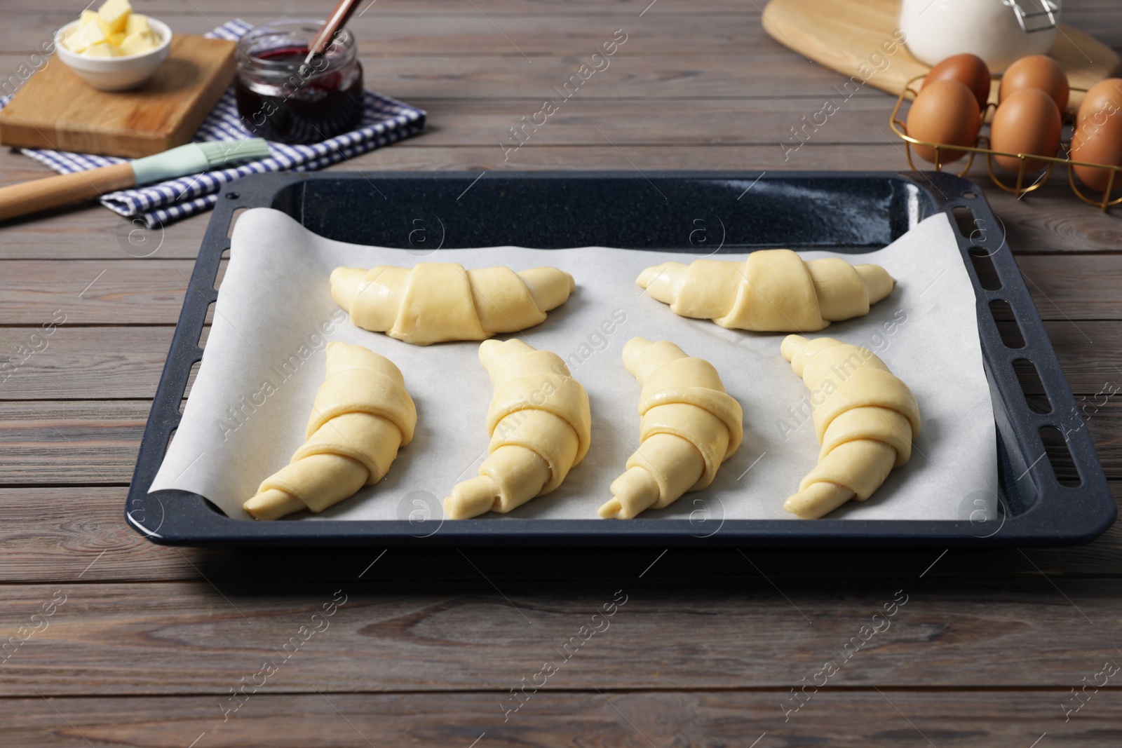 Photo of Raw croissants, ingredients and kitchenware on wooden table