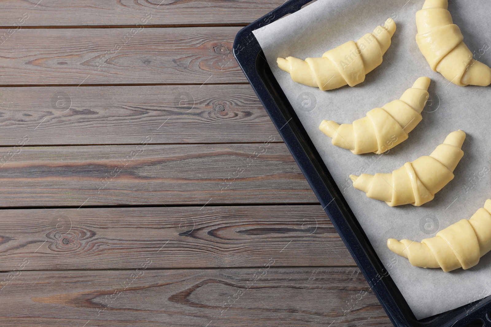 Photo of Raw croissants on wooden table, top view. Space for text