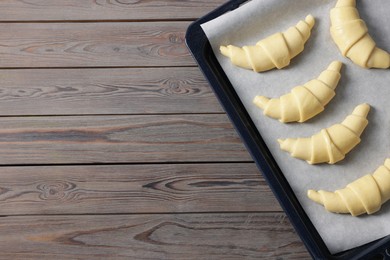 Raw croissants on wooden table, top view. Space for text