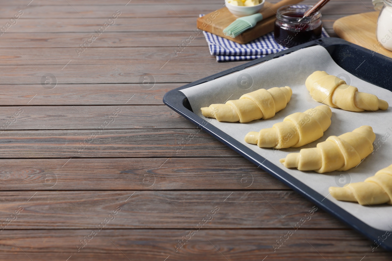 Photo of Raw croissants on wooden table, closeup. Space for text