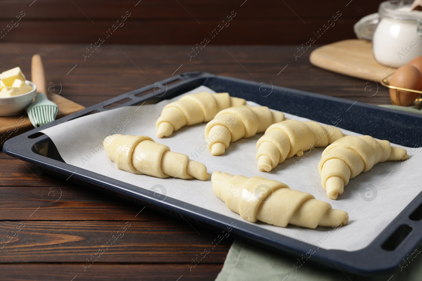 Photo of Raw croissants and ingredients on wooden table, closeup