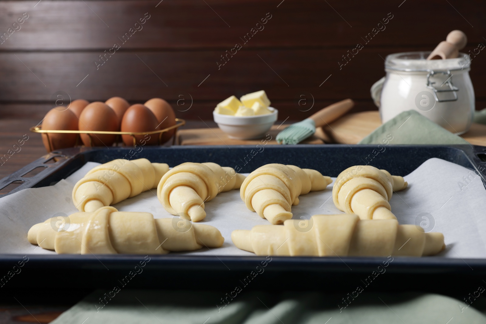 Photo of Raw croissants, ingredients and kitchenware on table, closeup