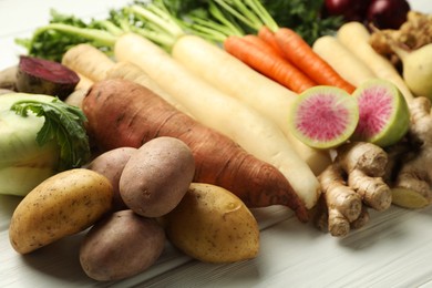 Photo of Different root vegetables on white wooden table, closeup